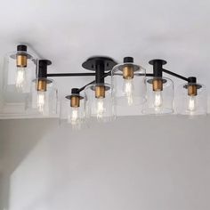 a chandelier with five lights hanging from it's sides and four clear glass jars on the bottom