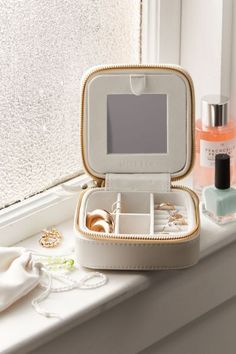 an open jewelry box sitting on top of a window sill next to other items