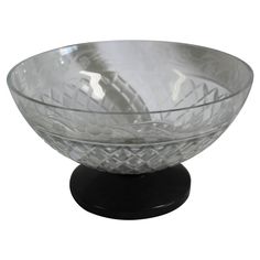 a clear glass bowl sitting on top of a black stand in front of a white background