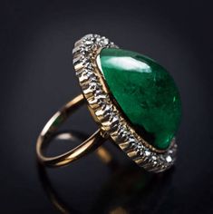 This antique ring from the early 1900s features a big cabochon cut natural emerald of a nice color surrounded by old cushion cut diamonds (H-I color, SI clarity) set in silver over 14K gold. The emerald measures 21.2 x 13 x 9.3 mm and is approximately 19.17 ct. Estimated total diamond weight is 2.20 ct. Ring size 7.25 (18 mm) sizable Antique Emerald Ring Oval Cabochon, Antique Emerald Ring With Oval Cabochon, Vintage Oval Emerald Ring With Diamond, Vintage Oval Emerald Ring With Rose Cut Diamonds, Antique Diamond Cabochon Rings, Elegant Oval Cabochon Emerald Collectible Ring, Vintage Diamond Cabochon Rings, Vintage Cabochon Emerald Ring For Anniversary, Vintage Diamond Rings With Cabochon