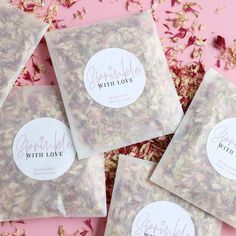 four bags of dried flowers sitting on top of a pink surface with the words love written in