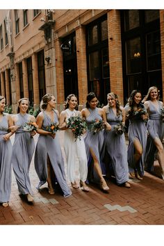 a group of bridesmaids in grey dresses walking down the street with their bouquets