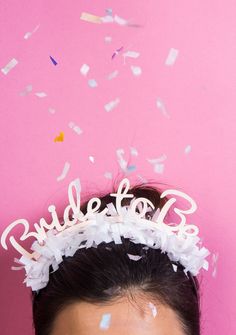 a woman wearing a tiara and confetti on her head with the word bride spelled out