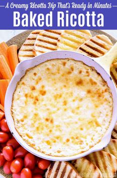 baked ricotta dip in a white bowl surrounded by crackers, tomatoes and carrots