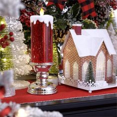 a christmas scene with a lit candle in front of a small house and decorations on the table