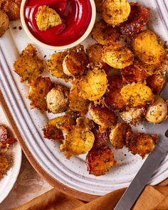 a white plate topped with fried food next to a bowl of ketch up sauce