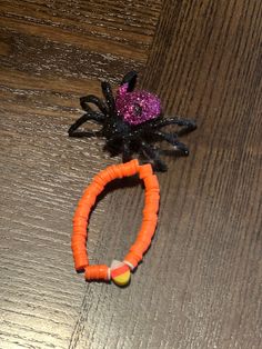 an orange bracelet with a spider on it and a candy bead in the middle