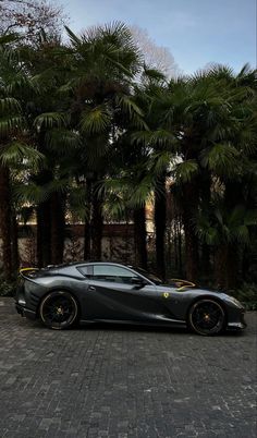 a black sports car parked in front of palm trees on a cobblestone street