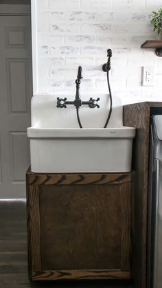 a white sink sitting under a faucet next to a wooden cabinet in a kitchen