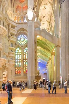 people are standing in the middle of a large building with stained glass windows and columns