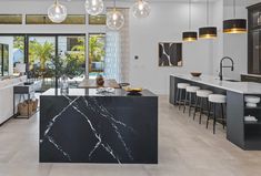 a kitchen with marble counter tops and bar stools next to an open living room