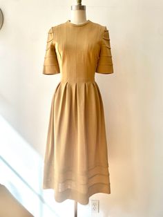 "1960s/70s Jean Varon for John Bates \"Knight\" dress. Rounded neckline, and half sleeves with seamed detailing. Beautiful tailoring, with 12 inverted pleats around the waist for a full skirt and defined waistline. Zips up the back. Warm camel color soft wool blend, the fabric is 80% acrylic and 20% wool. Both the Jean Varon and John Bates labels are intact at the neckline. A wonderful collectible dress!  Best for a size small, has a little stretch Bust:  33\" Waist: 26\" Hips: 40\" Length: 46\" Fitted A-line Midi Dress With Box Pleat, Elegant A-line Midi Dress For Vintage Fashion, Solid Color Half Sleeve Evening Dress, Evening Dress With Half Sleeves, Retro A-line Vintage Dress For Formal Occasions, Chic Short Sleeve Midi Dress With Box Pleat, Vintage A-line Dress With Pleated Waist, Formal Fitted Pleated Dress With Pleated Sleeves, Summer Midi Dress With Box Pleat And Short Sleeves