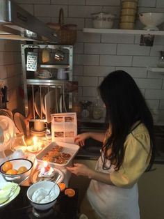 a woman is cooking in the kitchen with food on the counter and plates around her