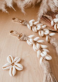 two white beads are attached to some tassels on a wooden table next to feathers