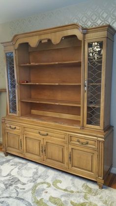 a large wooden china cabinet sitting on top of a rug