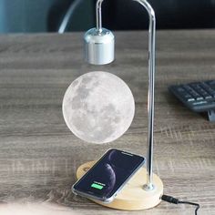 the moon lamp is next to a cell phone on a desk with a keyboard and mouse