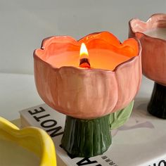 two ceramic candles sitting on top of each other next to a book and banana peel