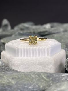 a yellow diamond ring sitting on top of a pile of white rocks with the stone in front of it