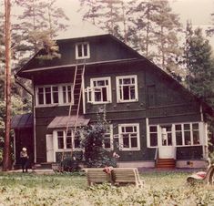 an old photo of a house in the woods with a ladder up to it's roof