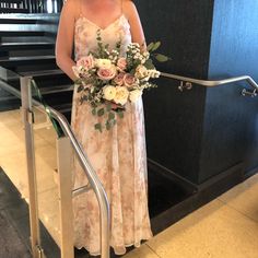 a woman in a dress is holding a bouquet on the stairs at an airport lobby