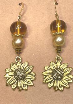 Long dangling gold sunflower earrings are ready for Fall! I've paired them with golden pearls and honey colored glass beads. The translucent beads shine in the sunlight while the gold pearls shimmer! The sunflower charms are detailed on one side only. Are you ready for some Golden Fall Sunflowers!? Gold Flower Charm Earrings For Summer, Gold Flower Earrings For Summer, Gold Sunflower Dangle Jewelry, Gold Drop Flower Earrings For Summer, Adjustable Gold Sunflower Earrings, Adjustable Gold Beaded Flower Earrings, Yellow Sunflower Dangle Earrings, Yellow Sunflower Design Dangle Jewelry, Yellow Sunflower Design Dangle Earrings