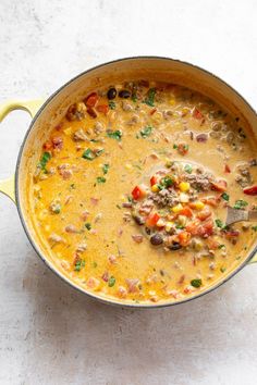 a large pot filled with soup on top of a white counter next to a wooden spoon