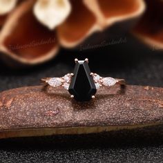 a black diamond ring sitting on top of a piece of wood next to some flowers