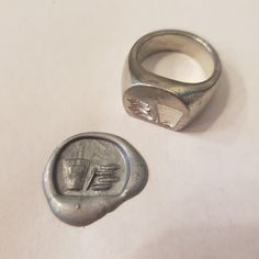 This signet ring is cast in lead-free pewter. The ring size when cast is 7.25. The sealing image is a cup of milk and a stack of cookies.       This is part of a series of signet rings I am making cast from lead-free pewter. Each master ring is hand sculpted to give a unique, rustic style, multi-dimensional relief image when used as a stamp to seal, with sealing wax. Unique Signet Ring For Promise With Lost Wax Casting, Wax Carved Signet Ring, Silver Handmade Collectible Signet Ring, Wax Carved Ring Silver Signet, Brutalist Sterling Silver Signet Ring Gift, Squaring The Circle, Pewter Ring, Resize Ring, Silver Ring Designs