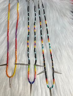 three different colored beads with metal spikes on top of them and one beaded necklace in the middle