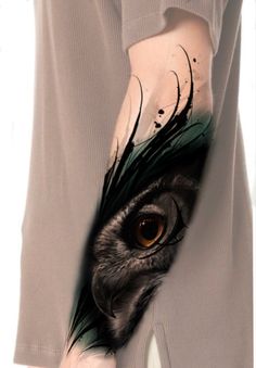 an owl's eye is seen through the arm of a person with tattoos on their arms