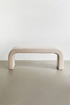 a white bench sitting on top of a cement floor