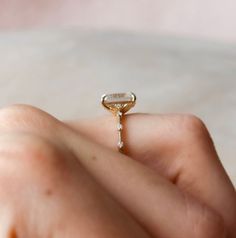 a woman's hand holding an engagement ring with a diamond in the middle and side