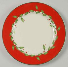 a red and green christmas plate with holly leaves on the rim, against a white background