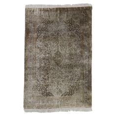 an antique rug with fringes on the edges and a medallion design in grey tones