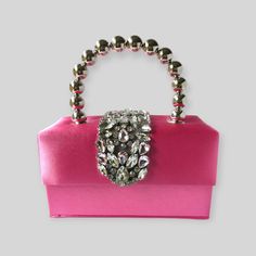 Plush bag is an absolute show stopper! You will be the centre of attraction with this stylishly built box bag made with beautiful, sleek and smooth silk fabric accentuated with rhinestones. It has a detachable chain sling to switch up your styling. Colour: Pink Dimensions (L x W x H) cm: 18 x 9 x 10 Weight: 491g Pink Evening Box Bag With Detachable Handle, Pink Square Box Bag For Party, Party Box Bag With Detachable Top Handle, Pink Top Handle Box Bag For Party, Designer Square Clutch For Evening, Chic Pink Box Bag For Party, Elegant Pink Box Bag For Evening, Designer Square Evening Clutch, Elegant Pink Evening Box Bag