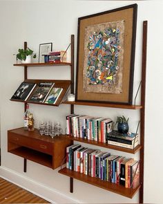 the bookshelf is full of books and magazines, along with a painting on the wall