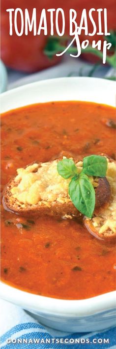 a bowl of tomato soup with bread on the side and tomatoes in the back ground