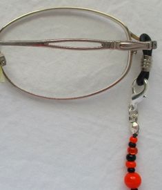 You'll always keep your reading glasses nearby using this mixed orange & black beaded eyeglass chain! 27" in length, made with glass beads, beading cord, metal lobster clasps, and adjustable rubber holders. Lobster clasps make it easy to change the rubber holders, and an extra pair of holders included with every purchase. This mixed orange & black beaded eyeglass chain will arrive in a gift box, ready to give as a present or to keep and store. Back to Beaded Eyeglass Chains Adjustable Black Beaded Glass Necklaces, Adjustable Metal Beaded Necklaces Nickel Free, Adjustable Black Beaded Glass Necklace, Adjustable Glass Beaded Necklace With Black Beads, Adjustable Nickel-free Metal Beaded Necklaces, Adjustable Metal Beaded Necklace Nickel Free, Silver Adjustable Beads With Lobster Clasp, Adjustable Silver Beads With Lobster Clasp, Adjustable Metal Beaded Necklace With Lobster Clasp