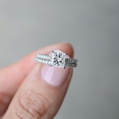 a woman's hand holding an engagement ring with two bands on top of it