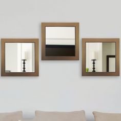 three mirrors hanging on the wall above a couch