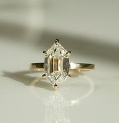 an emerald cut diamond ring on a white surface