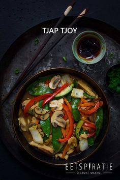 a pan filled with vegetables and sauce next to chopsticks on a table top