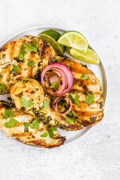 grilled chicken with cilantro, onion and lime garnish on a white plate