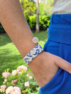 a close up of a person wearing a blue and white bracelet with a button on it