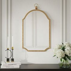 a vase with white flowers on a table next to a mirror and candle holder in a room