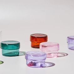 there are many different colored glass containers on the table