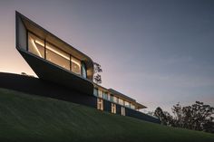 an unusual house on top of a hill at dusk with the sun shining through the windows