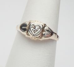 This is such a cute little ring from the 1960s! This would be a perfect April birthstone ring or just a cute little pinky or promise ring. Very cute and versatile! This ring features a single cut round diamond in the center of a heart outline. The diamond measures 2.10 mm and weighs approximately 0.04 carats. The diamond has VS clarity and H color. The ring is yellow gold all over but has white gold applied to the top around the heart and on the upper sides of the shank. The ring is stamped 14K Vintage Heart Ring For Promise, Vintage Promise Ring For Valentine's Day, Vintage Heart Ring With Birthstone For Valentine's Day, Vintage Birthstone Rings For Valentine's Day, Vintage Heart Cut Diamond Ring For Anniversary, Vintage Heart Cut Diamond Anniversary Ring, Vintage 14k Heart Ring For Valentine's Day, Vintage Heart Ring With Birthstone, Vintage Heart Cut Birthstone Heart Ring