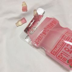 an open bottle of strawberry flavor gummy on a white sheet with two small candies