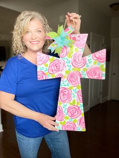 a woman holding up a paper cross with flowers on it